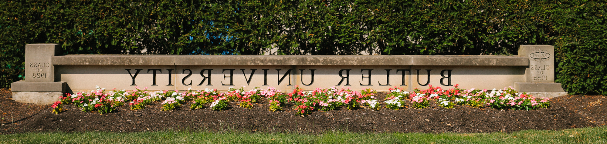 low stone wall with Butler University engraved and flowers in front